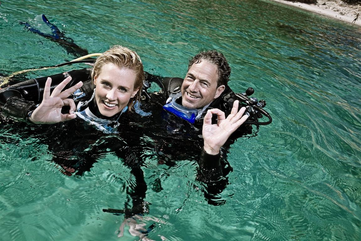 Deux plongeurs souriants dans des eaux cristallines, réalisant un geste "OK", symbole d'une plongée réussie à Hyères.